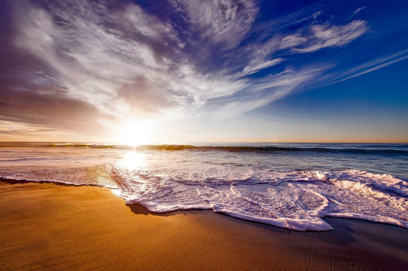 A beach with waves coming in from the ocean.