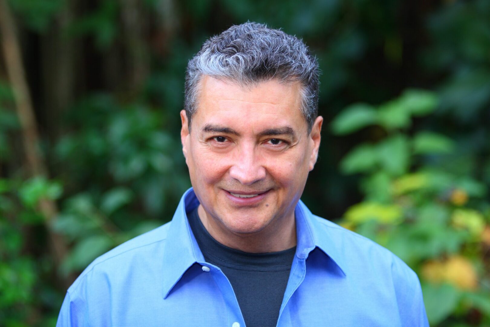 A man with grey hair wearing a blue shirt.